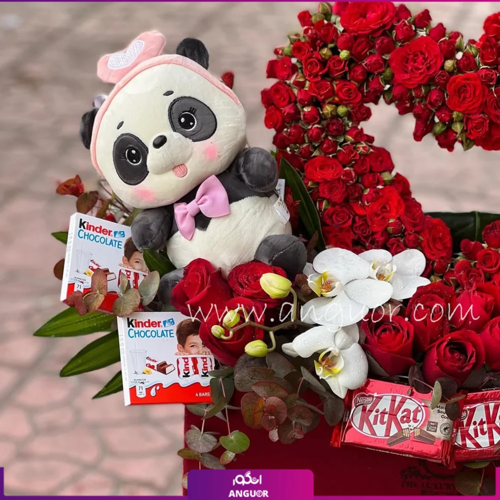 عروسک خرس زیبا با شکلات و ارکیده سفید و رزهای مینیاتوری قرمز در باکس گل عاشقانه